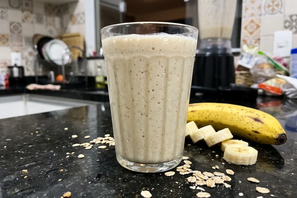 Vitamina de banana com aveia cremosa, preparada com leite, banana madura e aveia, servida em um copo.